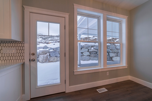 Looking out through a glass door and windows in a modern house at winter snow and a stone retaining wall
