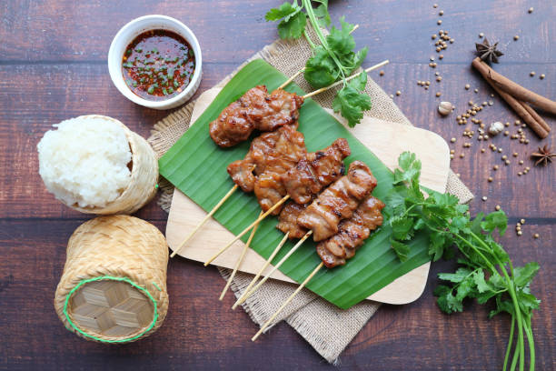 Grilled pork on skewer with sticky rice in Traditional container - Thai bbq pork served with sticky rice and spicy dipping sauce ( Moo Ping Khao Neow)