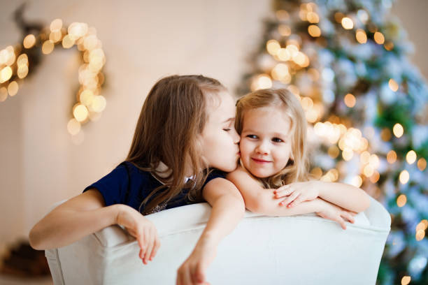 meninas na cadeira no fundo da árvore de natal. - 3 6 months - fotografias e filmes do acervo