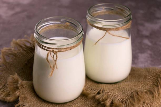 Two jars with fresh milk on a gray background. Copy space. Flat lay.