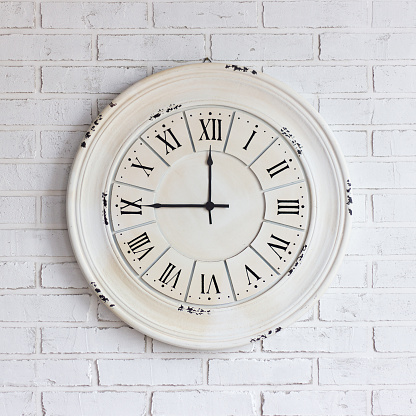 close up of vintage clock on white brick wall
