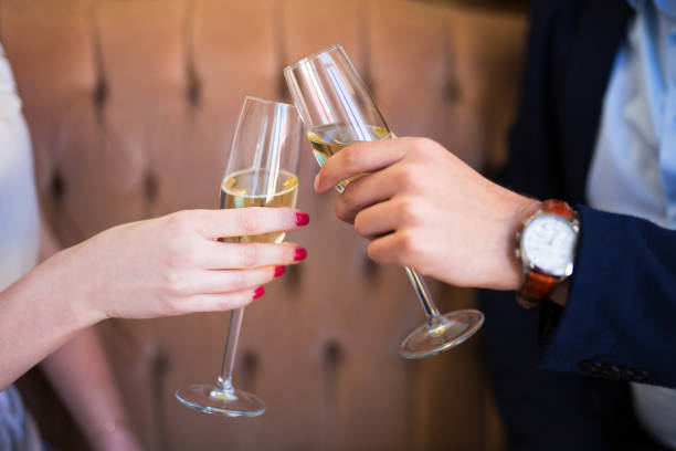 close up of champagne glasses in male and female hands stock photo