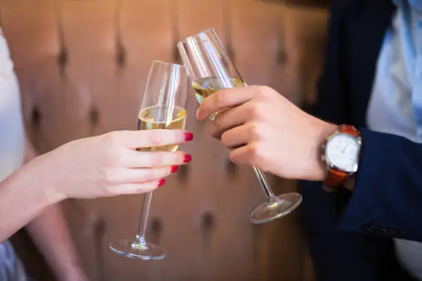 dating concept - close up of champagne glasses in male and female hands