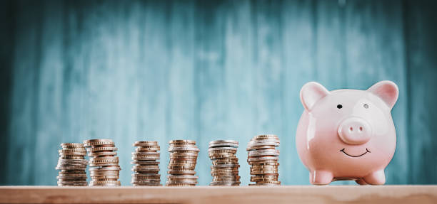istock Piggy bank with stacked coins on blue background 1275774291