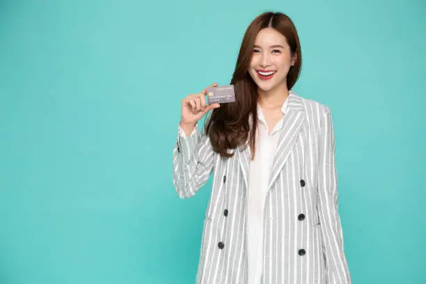 Young beautiful Asian woman smiling, showing, presenting credit card for making payment or paying online business, Pay a merchant or as a cash advance for goods, Cardholder or A person who owns a card