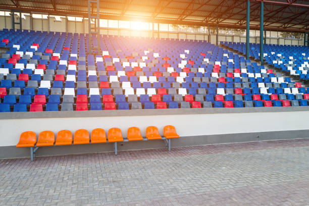 istock Stadiums amphitheater empty plastic seats in the stadium. Many empty seats for spectators in the stands for football fans and other outdoor sports.A place public government creates to the public. 1275777359