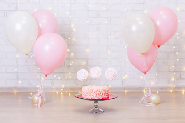 birthday celebration concept - cake over brick wall background with lights and colorful balloons