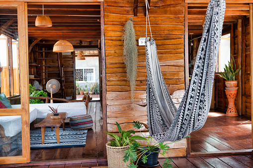 A luxury log cabin villa with wood paneling walls.  Decorated with Thai style furniture and an indoor hammock for relaxing in.