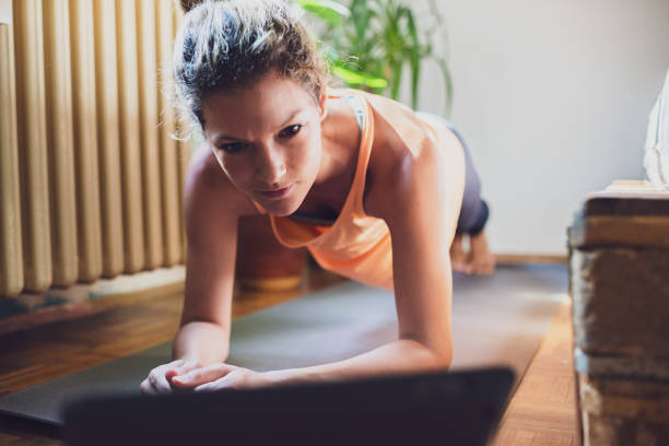 istock Girl training at home, doing plank and watching videos on digital tablet 1275784204