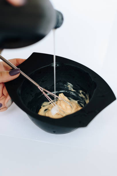 istock stylist kneads hair dye in a black container close up 1275785810
