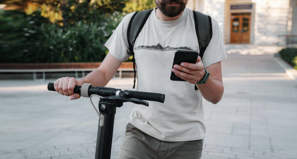 istock hipster man commuter with electric scooter outdoors in city, using smartphone 1275787527