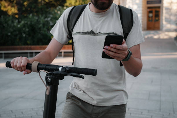 istock hipster man commuter with electric scooter outdoors in city, using smartphone 1275788940
