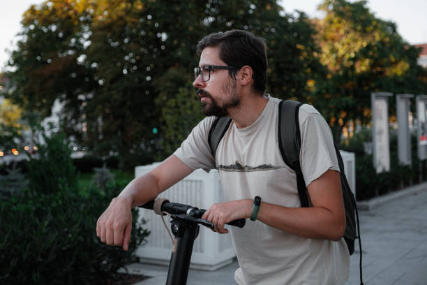 istock Attractive man riding a kick scooter at cityscape background 1275789160