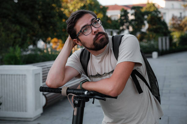 istock Attractive man riding a kick scooter at cityscape background 1275789255