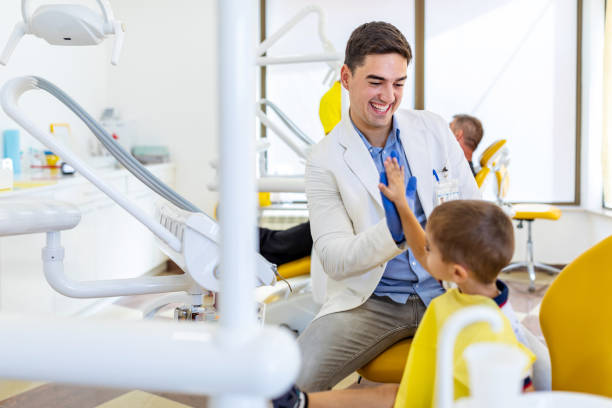 istock Pediatric dentist shake hands with young boy, congratulate patient for a successful operation in dental office. 1275789320