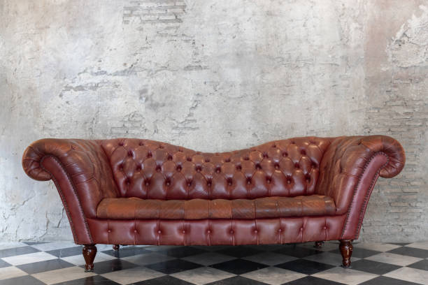 front view of luxury red leather sofa on checkered pattern marble tiles floor with brick cement wall front view of luxury red genuine leather sofa on checkered pattern marble tiles floor with brick cement wall red cushion covers stock pictures, royalty-free photos & images