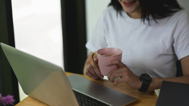 istock Cropped shot womanworking on laptop while drinking coffee at office. 1275791009