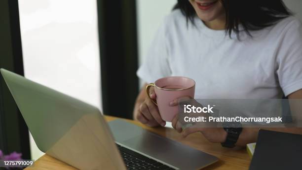 Cropped Shot Womanworking On Laptop While Drinking Coffee At Office Stock Photo - Download Image Now