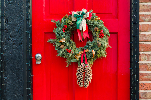 Front door to an English home painted red with a Christmas wreath, Xmas Garland