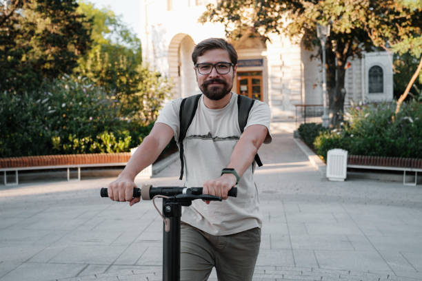 istock Attractive man riding a kick scooter at cityscape background 1275791700
