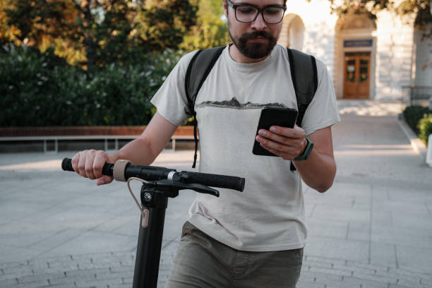 istock hipster man commuter with electric scooter outdoors in city, using smartphone 1275792233