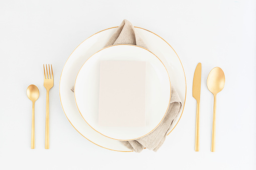 Festive christmas, wedding, birthday table setting with golden cutlery and porcelain plate. Blank card mockup. Restaurant menu template. Flat lay, top view