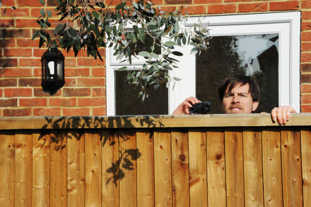 Middle aged man meeting smiling female neighbor in countryside and talking cheerfully to her over fence