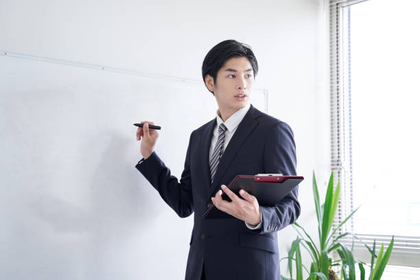 a japanese male businessman practicing his presentation - writing whiteboard men businessman imagens e fotografias de stock