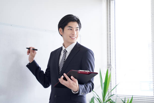 a japanese male businessman presenting with confidence - writing whiteboard men businessman imagens e fotografias de stock