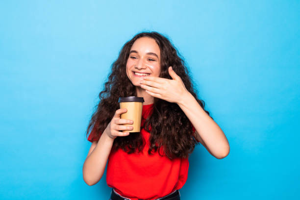 istock Young pretty woman holds takeout coffee stands over blue wall. 1275798083