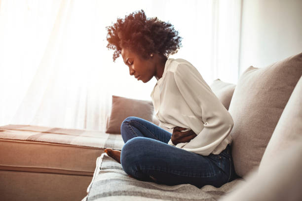 Woman having painful stomachache on bed, Menstrual period Woman lying on sofa looking sick in the living room. Beautiful young woman lying on bed and holding hands on her stomach. Woman having painful stomachache on bed, Menstrual period constipation photos stock pictures, royalty-free photos & images