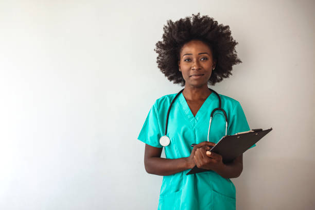 Studio shot of an attractive young nurse using a clipboard against a grey background.