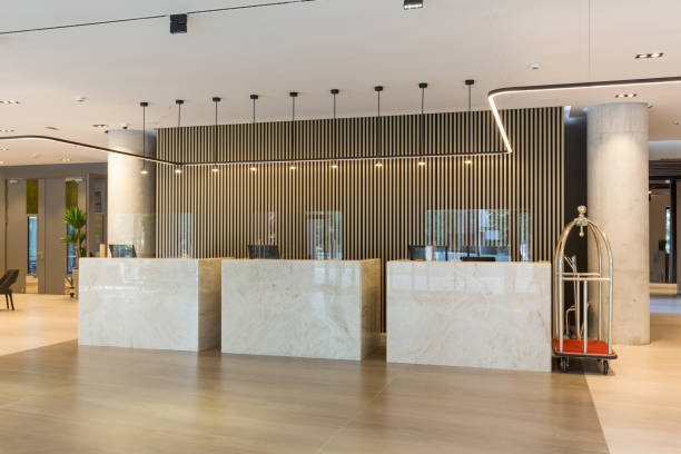 Interior of a hotel lobby with reception desks with transparent coronavirus plexiglass lexan clear sneeze guards Interior of a hotel lobby with reception desks with transparent coronavirus plexiglass lexan clear sneeze guards luxury hotel photos stock pictures, royalty-free photos & images