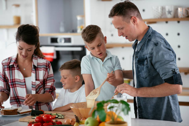 istock Mother and father making breakfast with sons. 1275800611