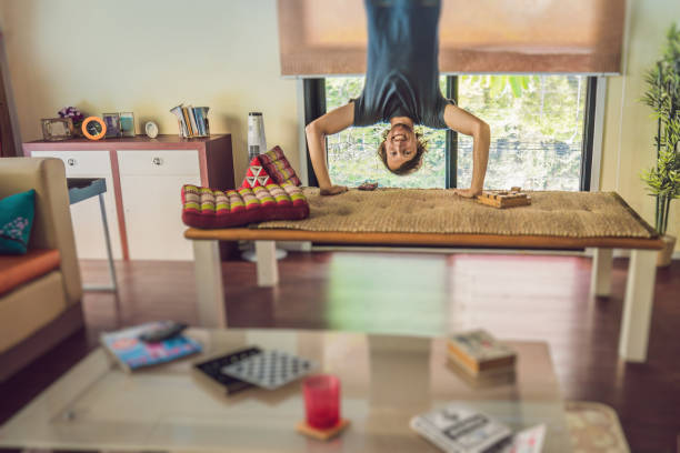 A man stands on his hands upside down in the living room.