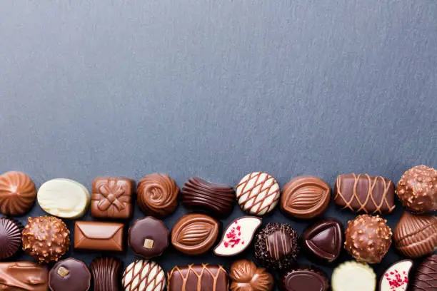 Assortment of fine chocolate candies, white, dark, and milk chocolate Sweets background. Copy space. Top view.