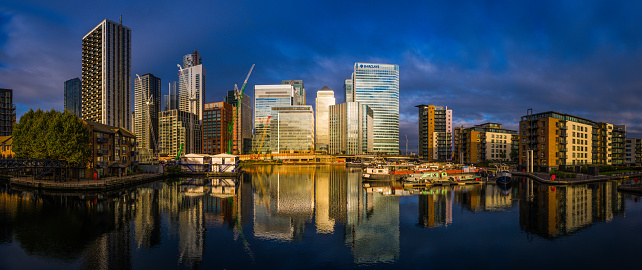 Golden light of dawn illuminating the crowded skyscraper cityscape of Canary Wharf and the modern housing developments in Docklands, London, UK.