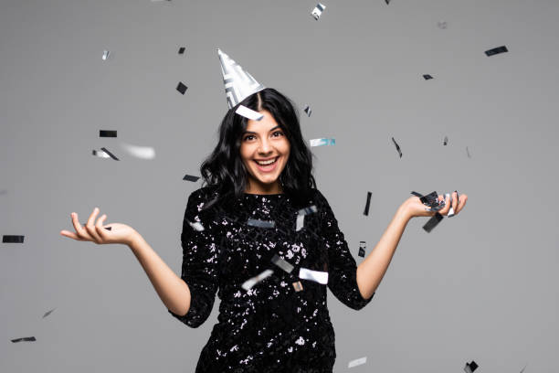 istock Beautiful young woman celebrating Birthday while confetti falling on her on gray background 1275808625