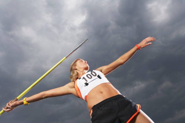 13930030 Female athlete throwing javelin against cloudy sky low angle view javelin stock pictures, royalty-free photos & images