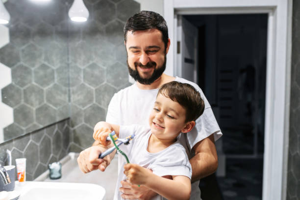istock Father and toddler brush their teeth together 1275811417