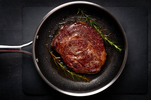 bife de carne de costela premium grelhado na panela, cozinhando bife na cozinha em um fundo escuro, vista superior - eye fillet - fotografias e filmes do acervo