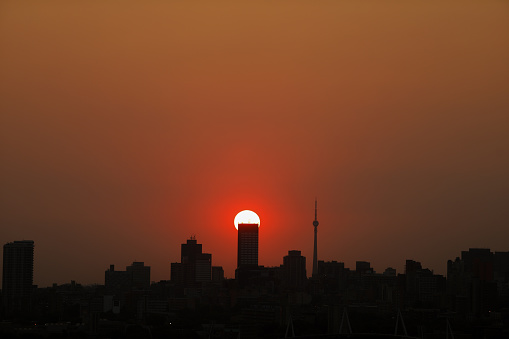 Johannesburg Skyline Silhouette at Sunset. The sun is behind the buildings.