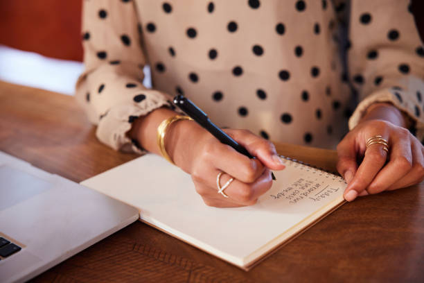 istock Businesswoman writing a to do list while working at a table 1275815324