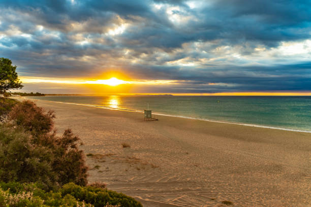 istock Beautiful sunset on a sandy beach with blue water 1275815686