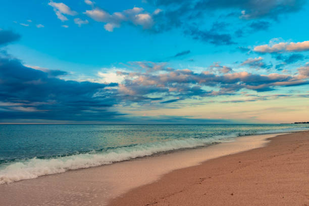 istock Beautiful sunset on a sandy beach with blue water 1275815692