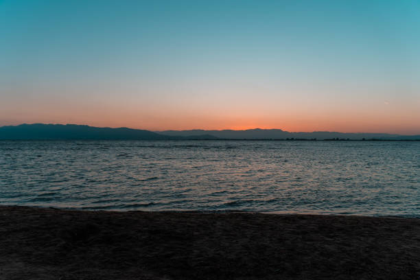 istock Beautiful sunset on a sandy beach with blue water 1275817198