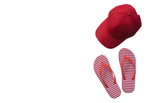 Photo of Red baseball cap isolated on white background. Striped flip flops. Mock up and summer.