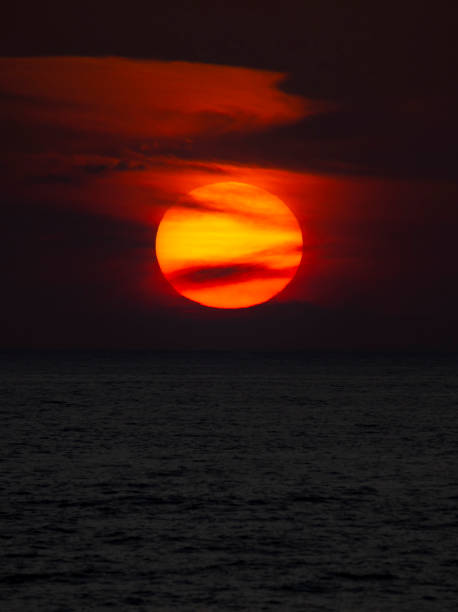 istock Big sun with black clouds, making a dark orange sunset background. 1275818665