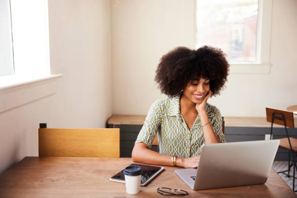 istock Smiling young woman working online with a laptop at a table 1275818709