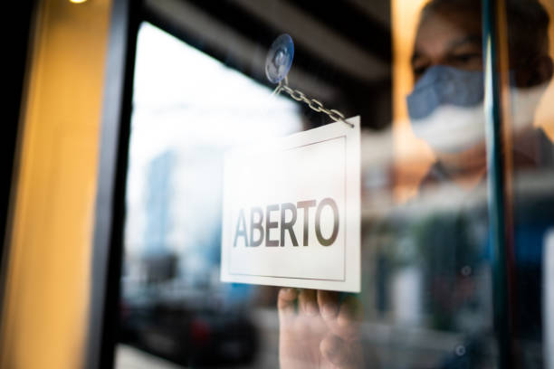 istock Business ower holding open sign (aberto) on storefront door 1275818716